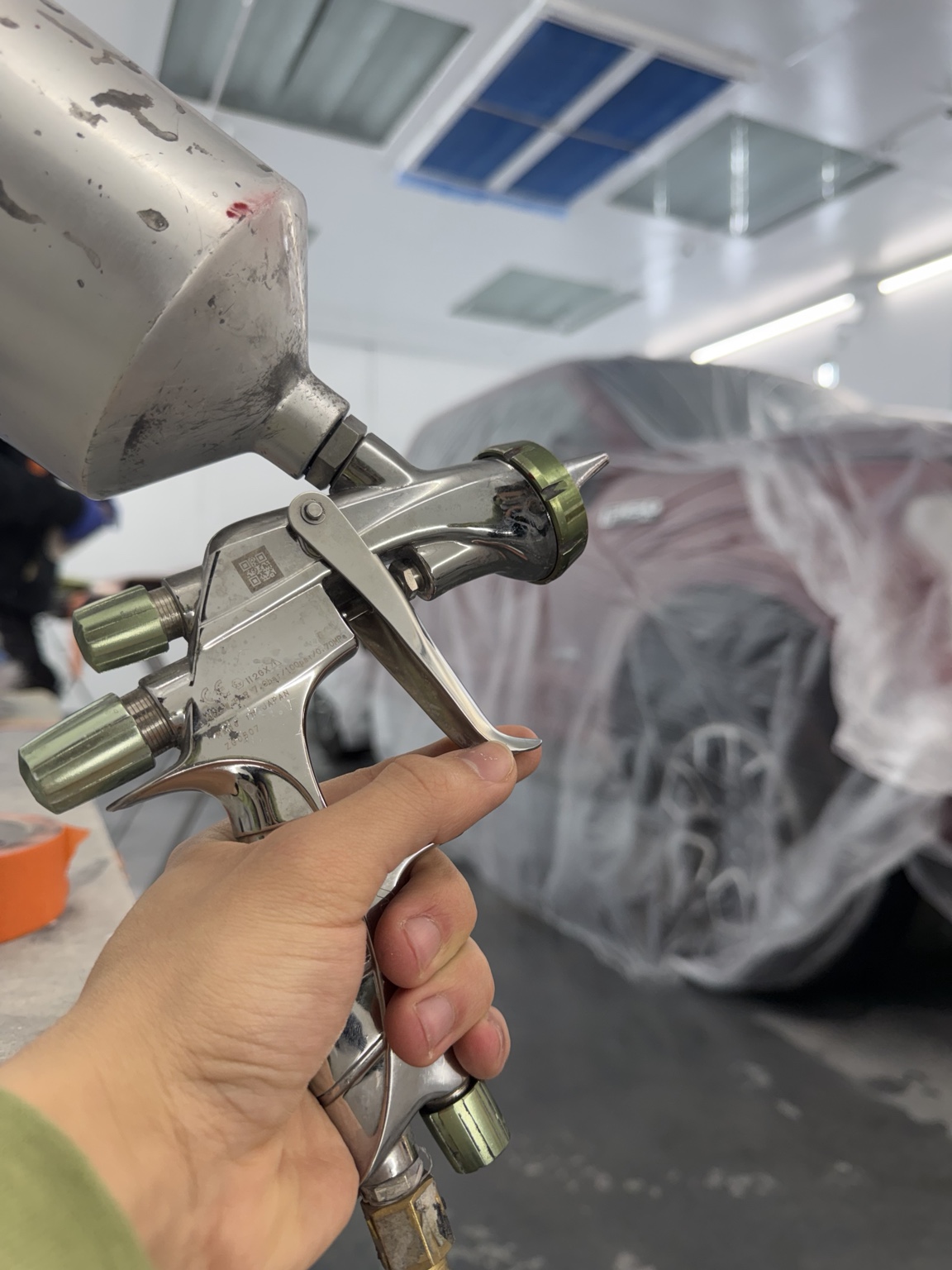 Automotive spray gun and masked vehicle in paint booth